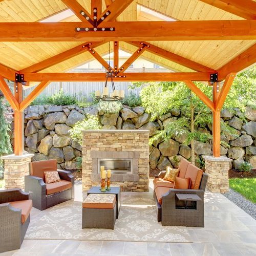 Exterior covered patio with fireplace and furniture. Wood ceiling with skylights.